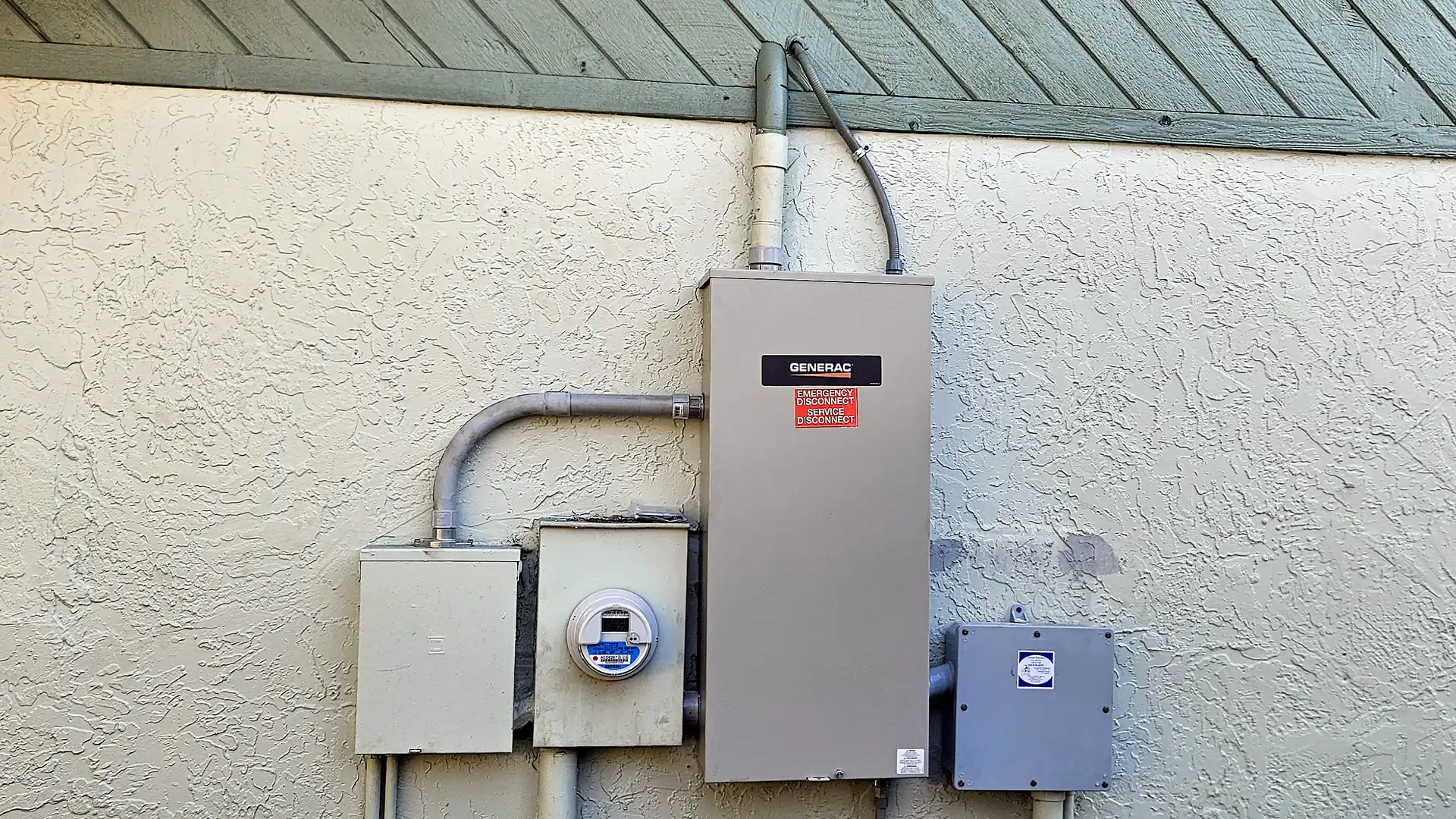 Generac automatic transfer switch installed next to the electric meter on a stucco home