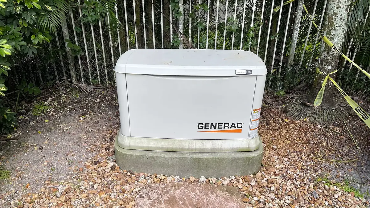 Generac home standby generator on a concrete pad in a fenced side yard