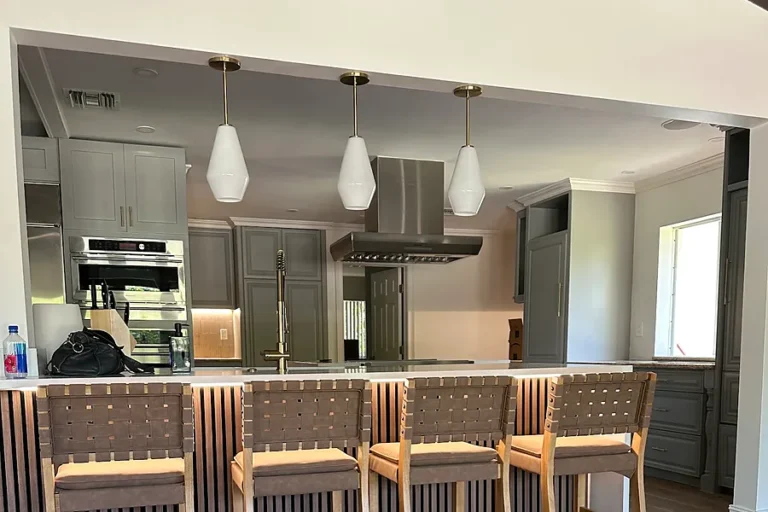 Three glass pendant lights over a kitchen island with bar stools