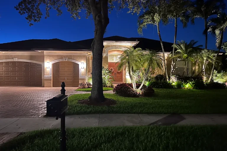 Front yard landscape lighting and palm tree uplights on a South Florida home at night