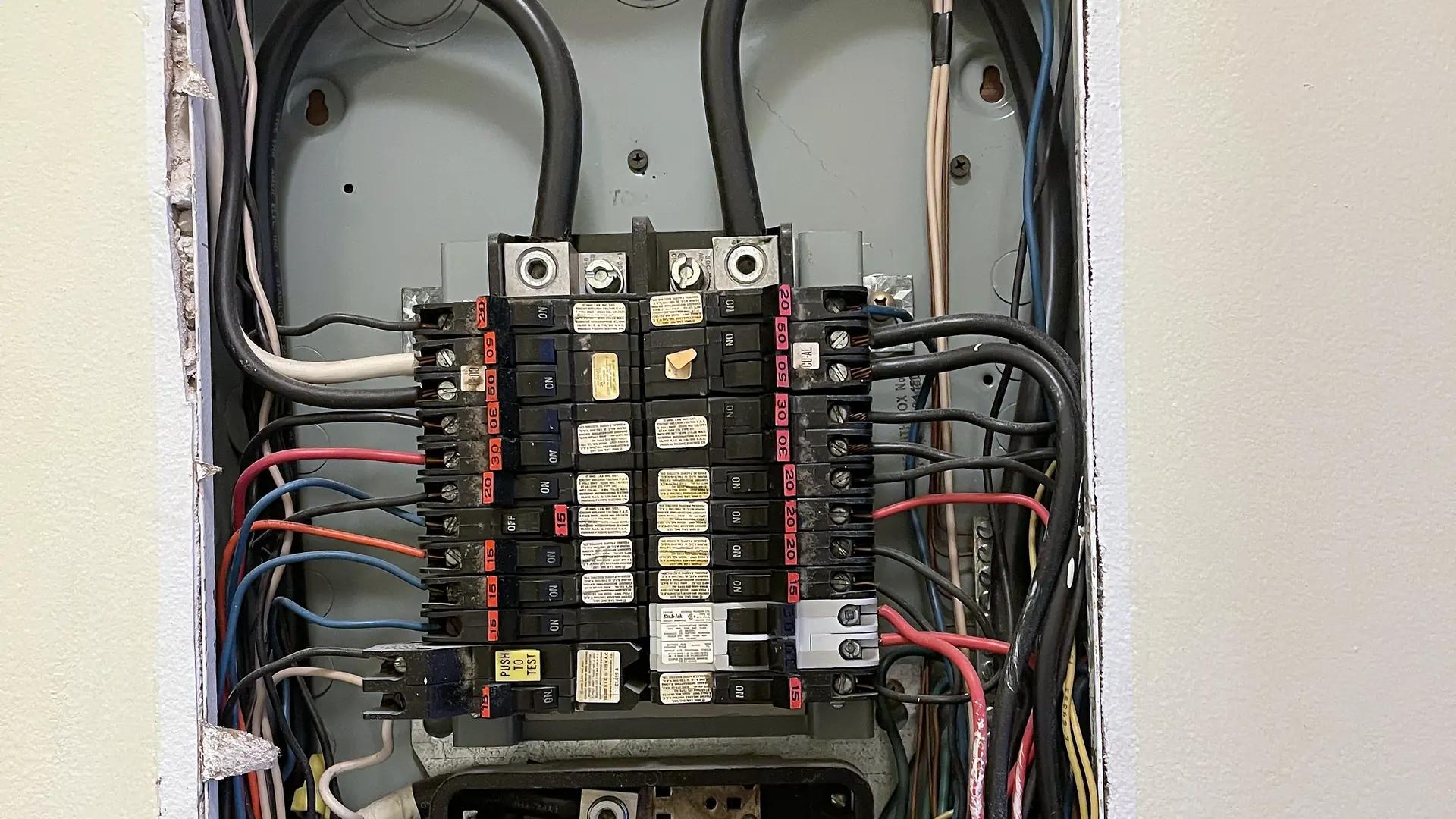 Outdated breaker panel with crowded wiring before replacement
