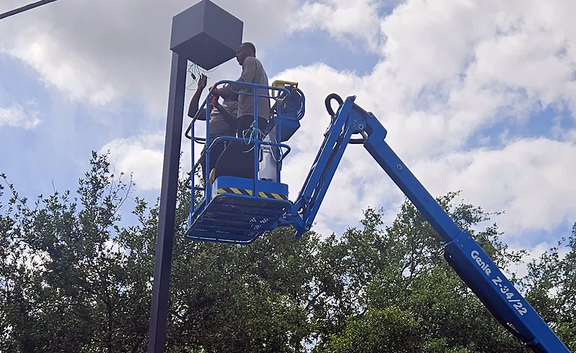 Electrician in a boom lift repairing a parking lot pole light